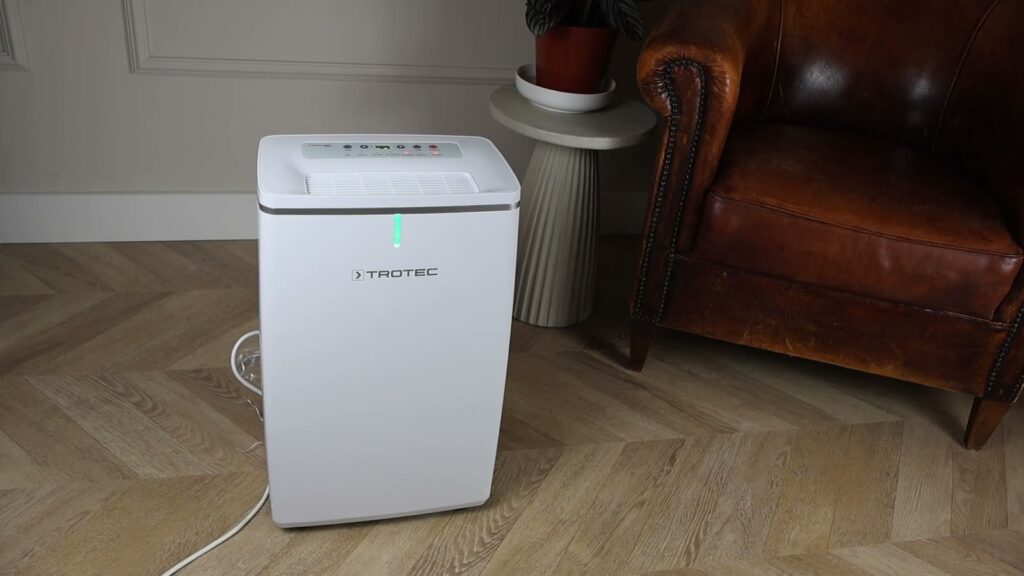 Trotec TTK 72 E luchtontvochtiger met groen lampje naast een lederen zetel